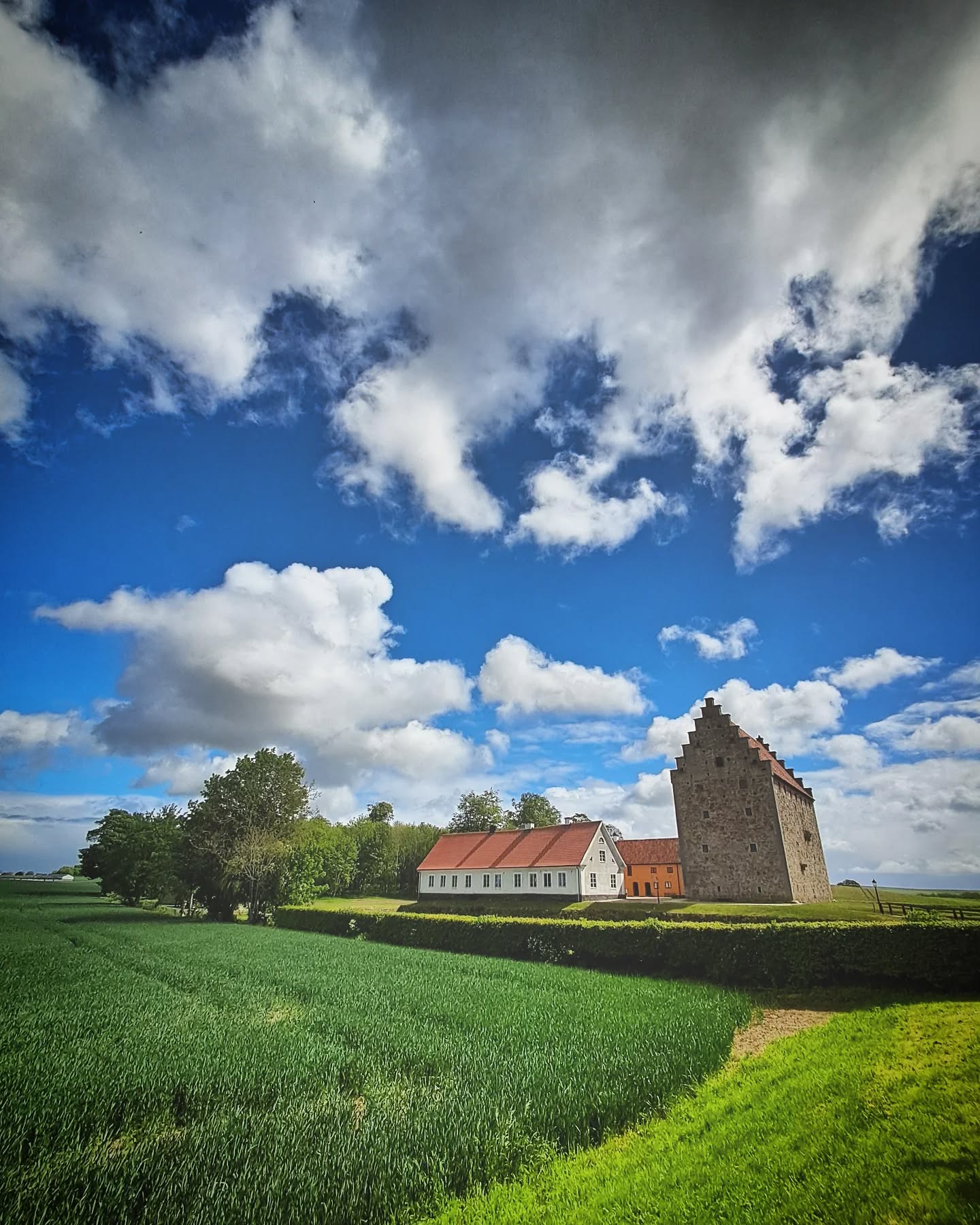 Gammalt stenhus i grönt landskap under dramatisk himmel